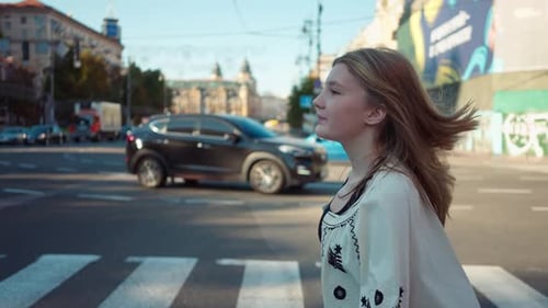 Imagem de rastreamento de vista lateral de uma adolescente sorridente e confiante atravessando a rua da cidade em Câmera lenta