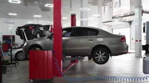 Vehicle Suspended on Hoist in Auto Repair Shop for Maintenance Mechanic Inspects Car on Lift Fixing