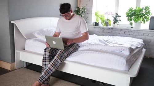 Young Adult Working on Laptop in Bedroom