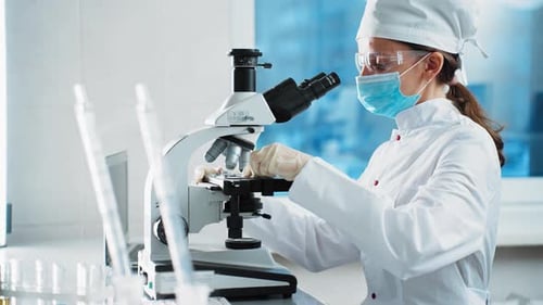 Female Scientist Using Microscope in Bright Laboratory