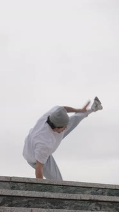 Breakdancer Performing Acrobatics on Building Ledge