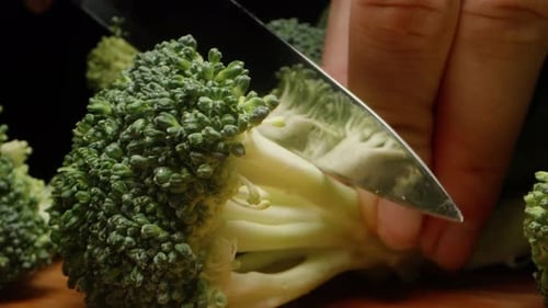 I cut the broccoli bush into small inflorescences. Slow motion . Dolly slider extreme close-up.
