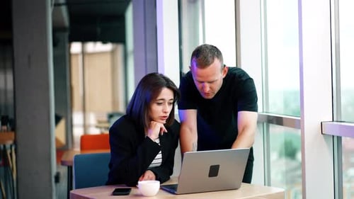 Colleagues Collaborating on Laptop in Modern Office
