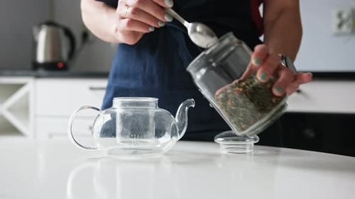 Girl Pouring Green Tea Into Teapot In The Kitchen