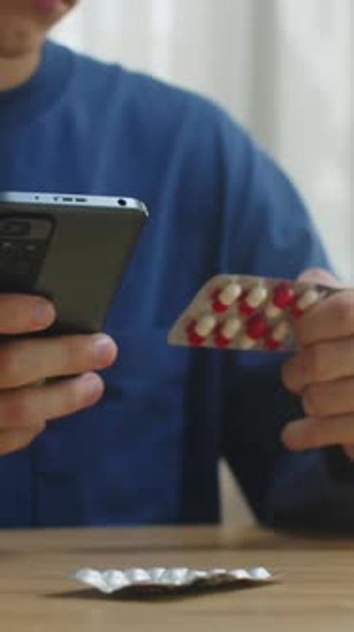 Young Adult with Pills and Phone Indoors