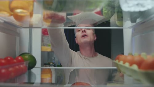 Young Man Searching Through Refrigerator for Food