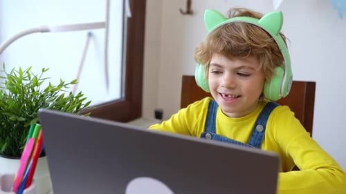 Young Boy with Headphones Using Laptop at Home