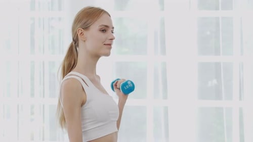 Beautiful young woman workout with lift up dumbbell for muscle while motivation and determined.