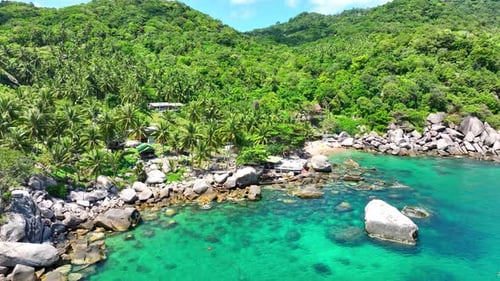 Flying over sea waters along the rocky coastline in tropical island.