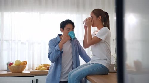 Young Couple Chatting and Drinking Coffee in Kitchen