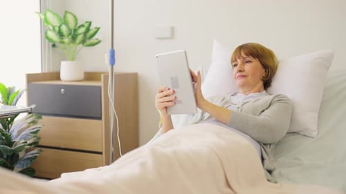 Woman Using Tablet Computer Lying in Hospital Bed