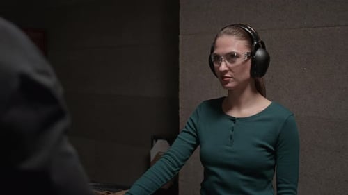 Woman at Indoor Shooting Range Listens to Instructor