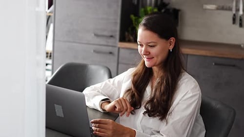 Woman Video Conferencing on Laptop in Modern Kitchen