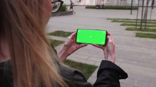 Point of View of Woman Holds Horizontal Mobile Phone Two Hand Outdoor Urban City Use Green Screen
