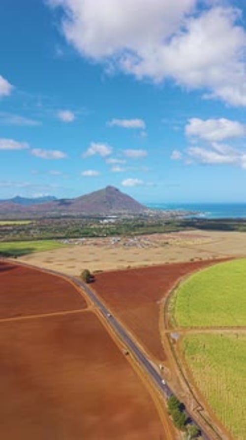 Vertical aerial shot of a road on Mauritius island landscape with coastal lagoons, towns.
