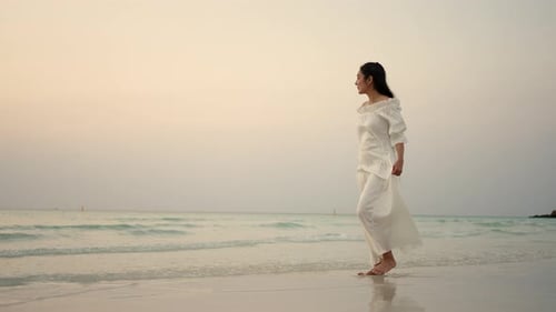 4K Young Asian woman walking on tropical island beach at summer sunset