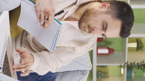 Adult Writes in Notebook, Using Laptop