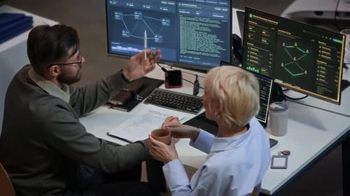 Zwei Ingenieure diskutieren im Cybersicherheitsbüro über Netzwerksysteme auf Computern