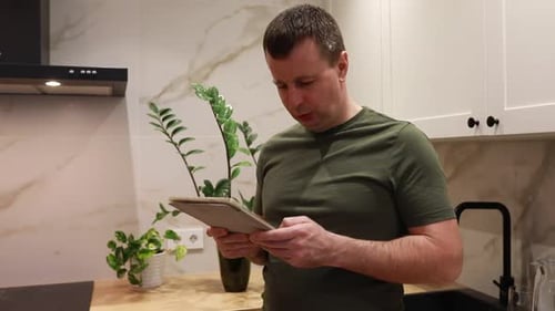 Man Uses Tablet in Modern Kitchen