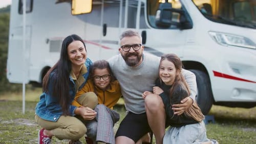 Happy family poses in front of camper van