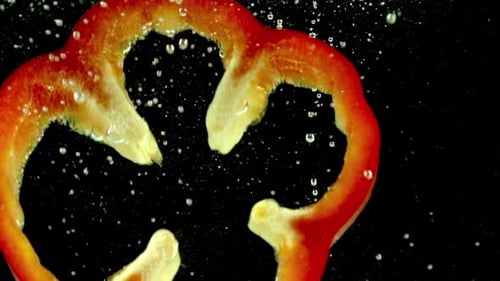 Red Bell Pepper Slices Falling Into Water in Slow Motion