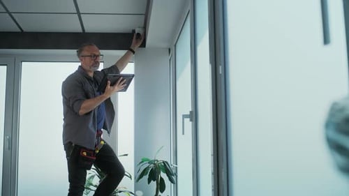 Male Installer Sets Up CCTV Camera in Office Using Tablet Computer