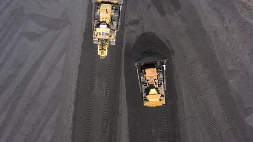 Luftaufnahme von Bulldozern, die Kohle auf ein Wärmekraftwerk lenken