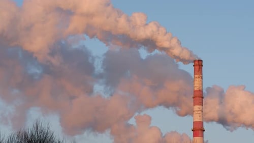 Striped Smokestack Releasing a Cloud of Smoke in Blue Sky