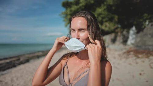 Woman on Beach Removing Surgical Face Mask
