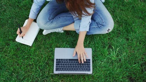Woman Student Working on Laptop Computer and Writing Notes in Notebook On