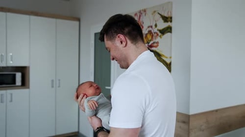 Smiling Father Holding Newborn Baby Indoors