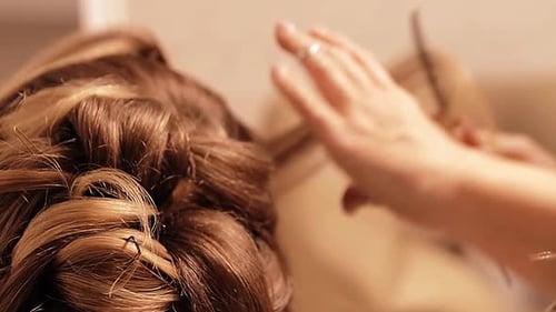 a hairstylist fixes and prepares the bride's hair for the wedding a beautiful wedding hairstyle