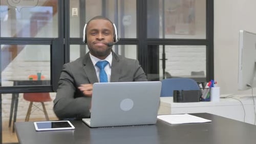Man in Headset Working at Laptop in Office