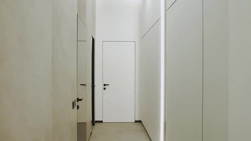A Hallway in a Building with White Walls a Wooden Door and a Handle