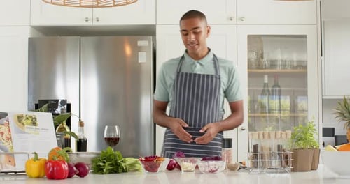Vlogger de cuisine biracial en tablier parlant et filmant dans la cuisine