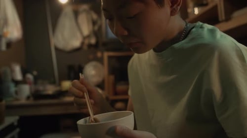 Chinese Woman Eating Stir-Fry with Chopsticks in Tiny Flat