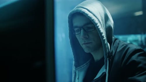 Young Man in Hoodie Uses Computer at Night