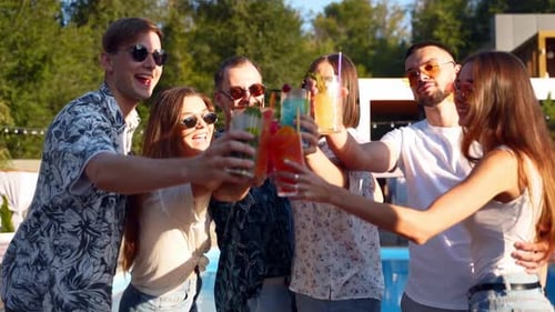 Friends Toasting Cocktails by Pool on Sunny Day