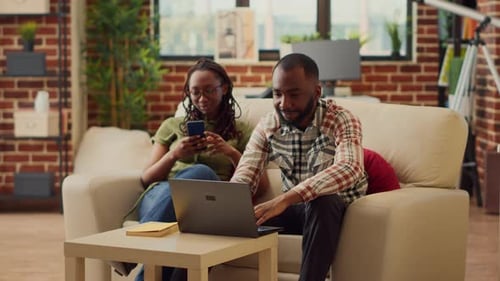 Couple Relaxing At Home Using Technology