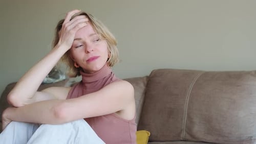 Woman Sitting Thoughtfully on Couch in a Home