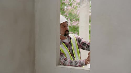 Indian architect with mustache uses water level measuring device. Intended to check slope of a concr