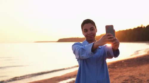 Young Adult Taking Selfie at Sunset on Beach
