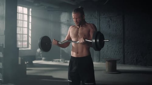 Screaming muscular man weightlifting barbell at dark gym training bodybuilding motivation