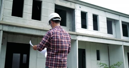 Architect Reviews Building Plans at Construction Site