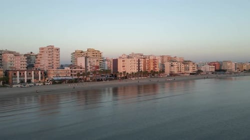 Golden hour sunset light reflects off buildings on Adriatic Sea beach