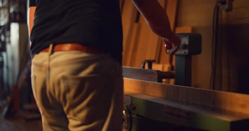 Woodworker sands timber with heavy machinery in workshop filmed on red camera