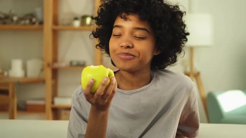 Happy Pretty Girl Biting Green Apple at Home