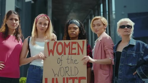 Group of Women Hold 'Unite' Sign in Urban Setting