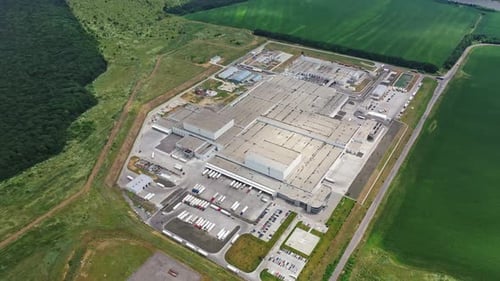 Big territory of industrial complex surrounded by green fields and forests.