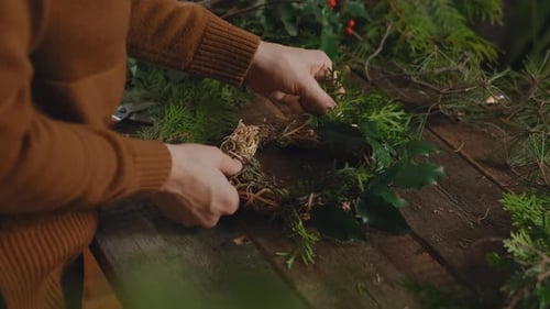 Woman florist making Christmas wreath in floral workshop.